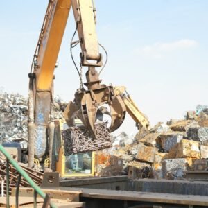 An excavator working on a pile of scrap metal